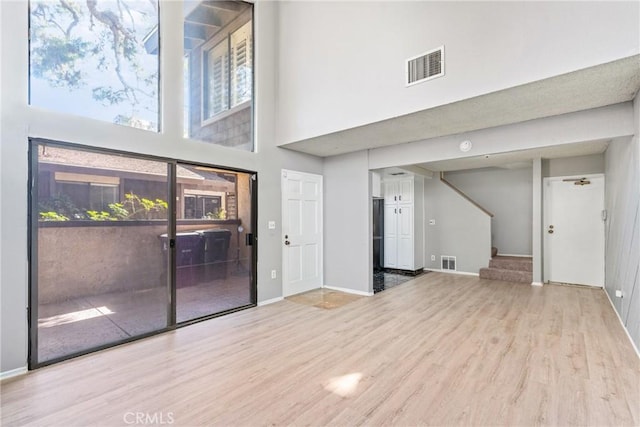 unfurnished living room featuring light hardwood / wood-style flooring and a high ceiling