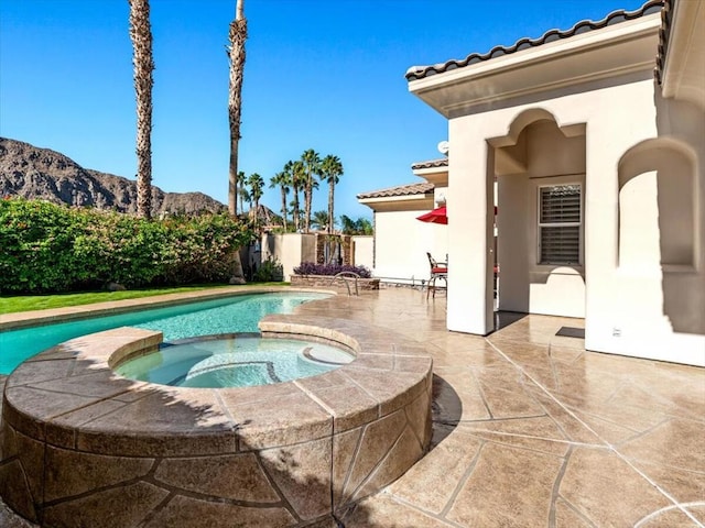 view of pool featuring an in ground hot tub, a mountain view, and a patio area