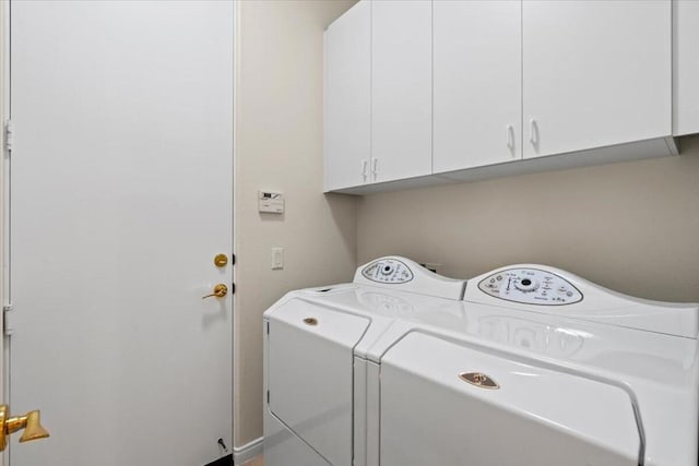 clothes washing area with washer and dryer and cabinets