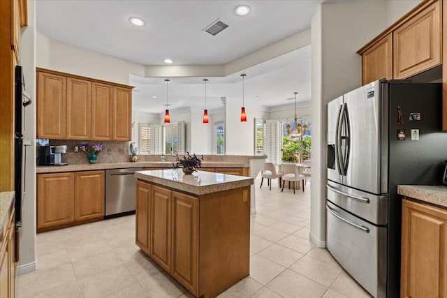 kitchen featuring a kitchen island, ornamental molding, hanging light fixtures, and appliances with stainless steel finishes