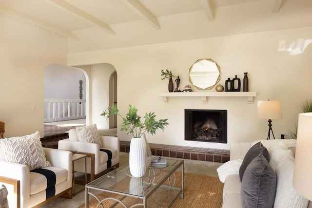 living room with a tiled fireplace and beamed ceiling