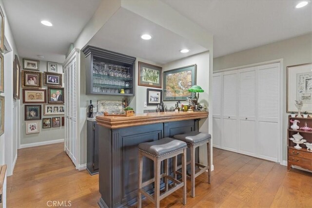 bar with wooden counters, light hardwood / wood-style flooring, and gray cabinetry