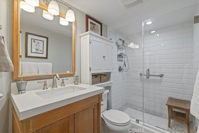 bathroom featuring vanity, toilet, and a shower with door