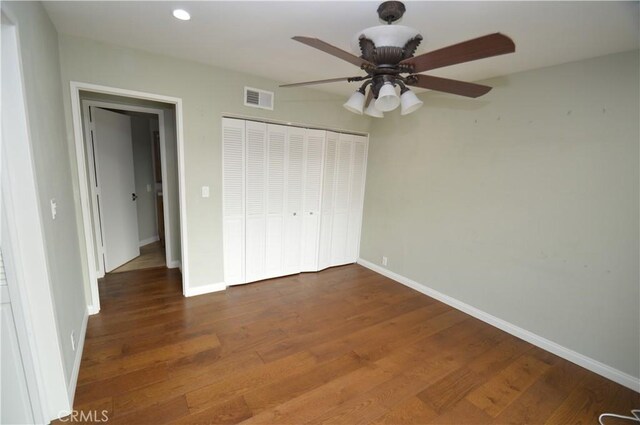 unfurnished bedroom with ceiling fan, dark hardwood / wood-style flooring, and a closet