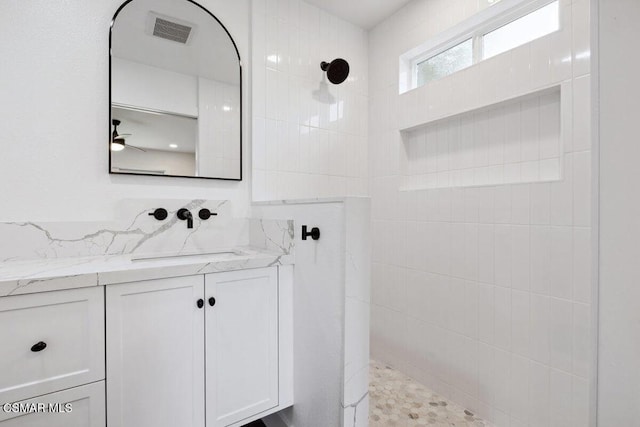 bathroom featuring tiled shower, vanity, and ceiling fan