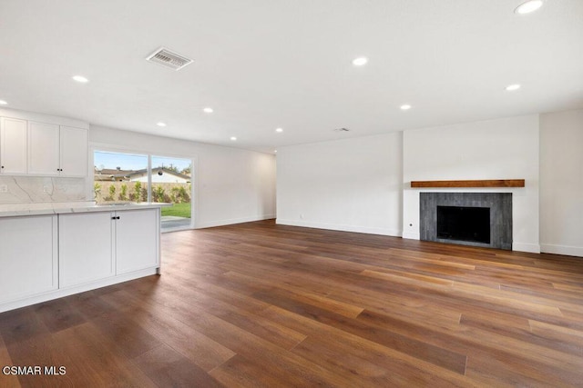 unfurnished living room featuring wood-type flooring and a tile fireplace