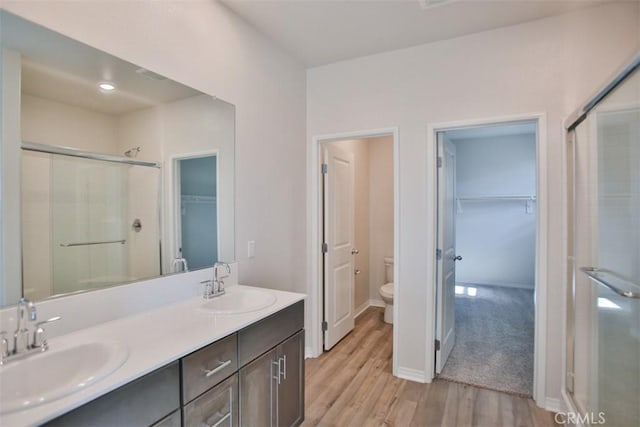 bathroom with wood-type flooring, vanity, toilet, and a shower with shower door