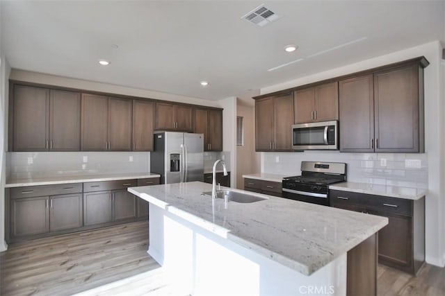 kitchen featuring appliances with stainless steel finishes, light hardwood / wood-style floors, a kitchen island with sink, and sink