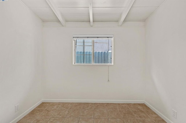 spare room featuring beamed ceiling and light tile patterned floors