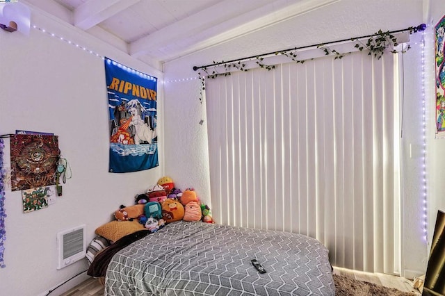 bedroom with beamed ceiling and hardwood / wood-style flooring