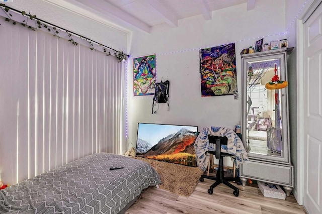 bedroom with beamed ceiling and light hardwood / wood-style floors