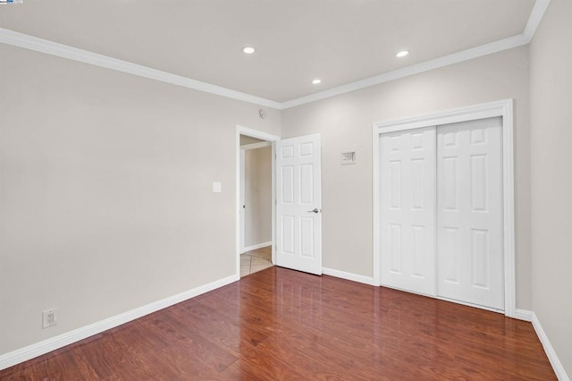 unfurnished bedroom with dark hardwood / wood-style floors, crown molding, and a closet