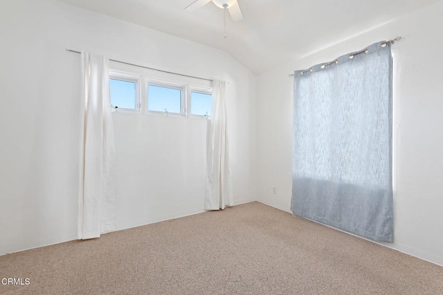 carpeted spare room featuring vaulted ceiling and ceiling fan