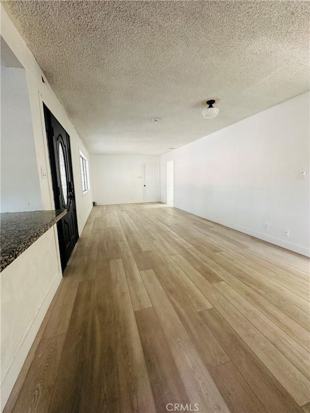 unfurnished living room with a textured ceiling and light hardwood / wood-style flooring