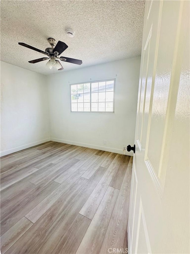 unfurnished room featuring ceiling fan, light wood-type flooring, and a textured ceiling