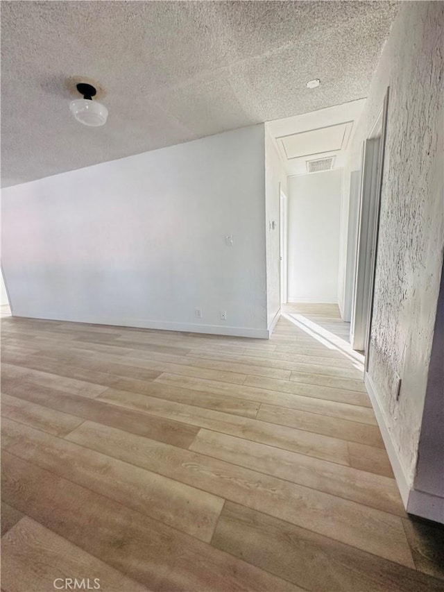 corridor with a textured ceiling and light hardwood / wood-style floors