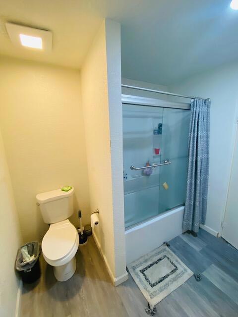 bathroom featuring hardwood / wood-style flooring, toilet, and shower / tub combo with curtain