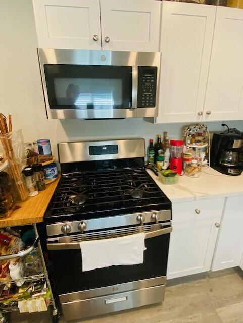 kitchen featuring white cabinets, appliances with stainless steel finishes, and light stone counters