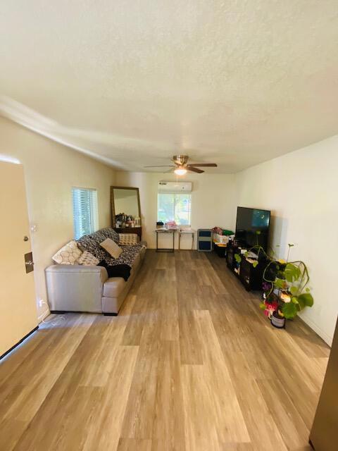 unfurnished living room featuring a textured ceiling, ceiling fan, and light hardwood / wood-style flooring