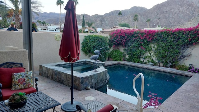 view of pool featuring a mountain view, an in ground hot tub, and a patio area