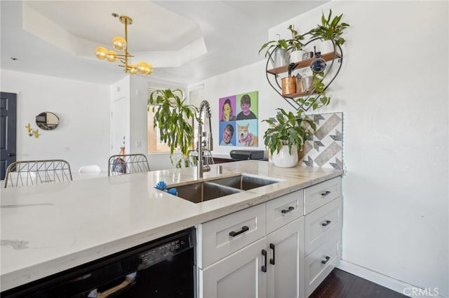 kitchen featuring pendant lighting, white cabinets, a raised ceiling, sink, and black dishwasher