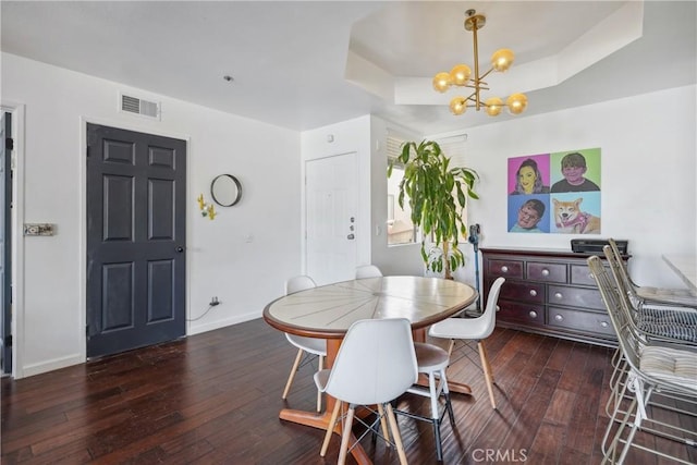 dining room featuring a tray ceiling, dark hardwood / wood-style flooring, and a notable chandelier