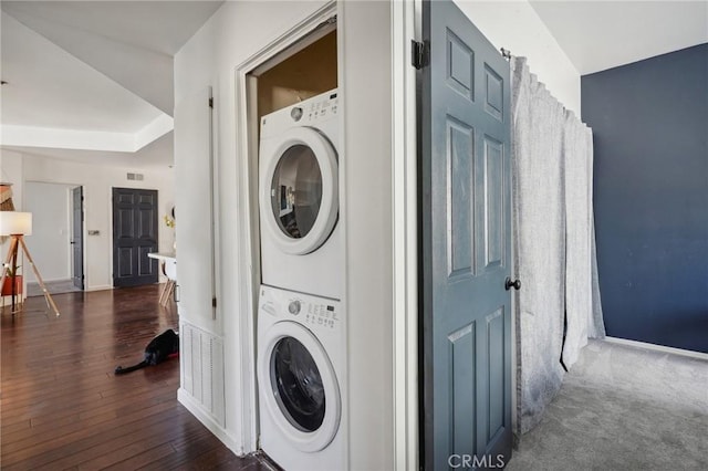 clothes washing area with dark hardwood / wood-style floors and stacked washer and clothes dryer