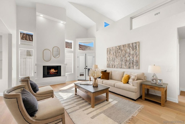 living room with light hardwood / wood-style floors and a towering ceiling