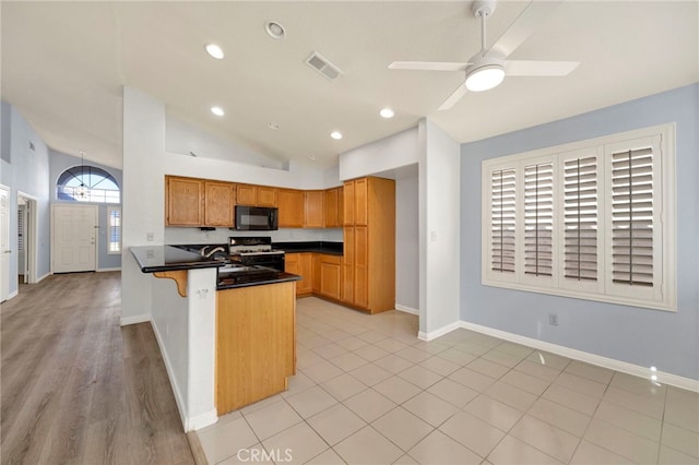 kitchen with a breakfast bar, black appliances, vaulted ceiling, ceiling fan, and kitchen peninsula