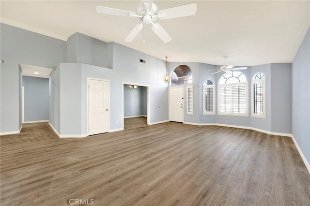 unfurnished living room featuring hardwood / wood-style flooring, ceiling fan, and a high ceiling