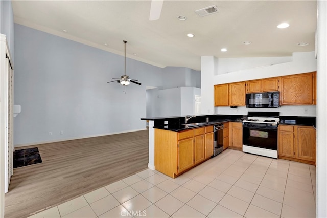 kitchen featuring kitchen peninsula, light hardwood / wood-style floors, high vaulted ceiling, and black appliances