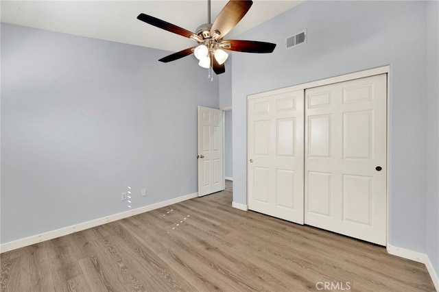 unfurnished bedroom with light wood-type flooring, a closet, high vaulted ceiling, and ceiling fan