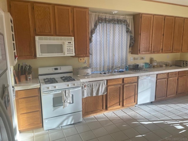 kitchen with sink, light tile patterned floors, and white appliances