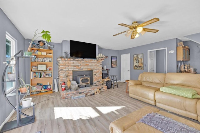 living room with ceiling fan, light hardwood / wood-style floors, and a wood stove