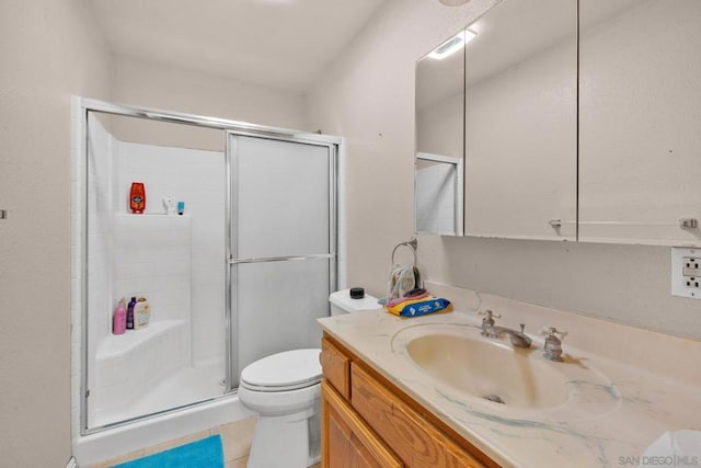 bathroom with tile patterned floors, vanity, toilet, and a shower with door