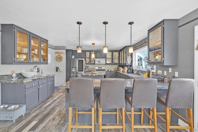 kitchen with a kitchen bar, appliances with stainless steel finishes, dark hardwood / wood-style flooring, and pendant lighting