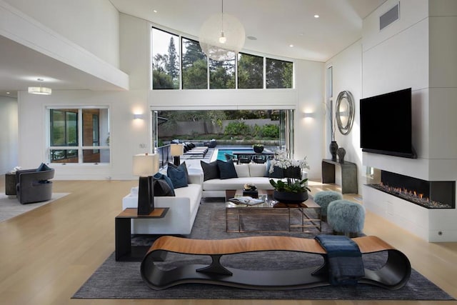 living room with light wood-type flooring and high vaulted ceiling