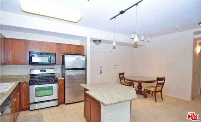 kitchen featuring appliances with stainless steel finishes, light colored carpet, sink, a center island, and hanging light fixtures