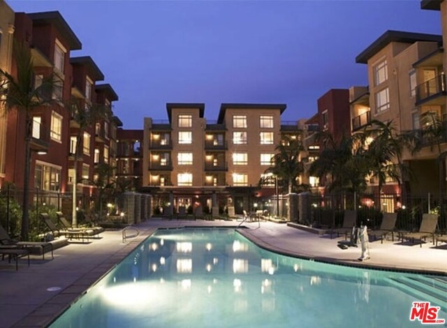 pool at dusk with a patio area