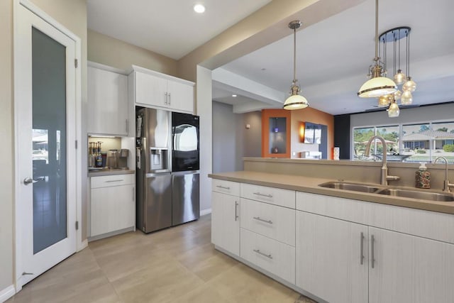 kitchen featuring stainless steel refrigerator with ice dispenser, sink, hanging light fixtures, and white cabinets