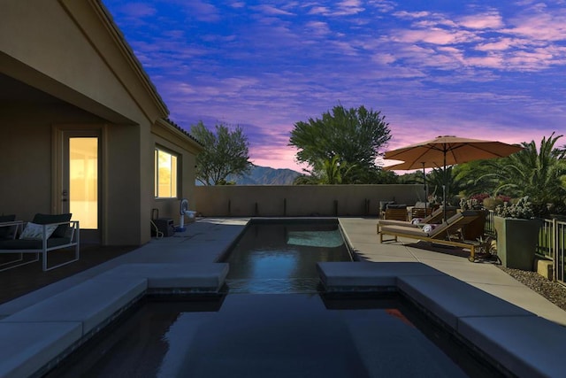 pool at dusk with a mountain view and a patio area