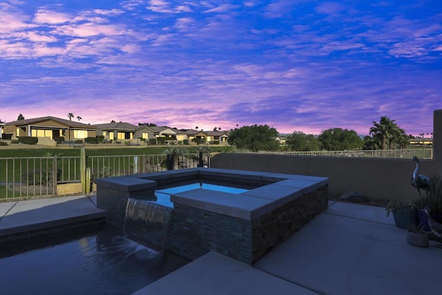 pool at dusk with an outdoor hot tub