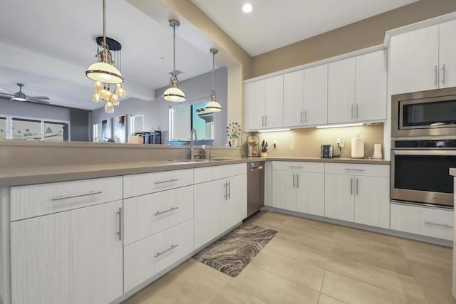 kitchen featuring stainless steel appliances, white cabinetry, decorative light fixtures, and sink