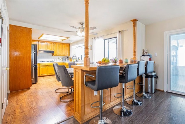 kitchen with stainless steel refrigerator, decorative backsplash, a breakfast bar, and light hardwood / wood-style floors