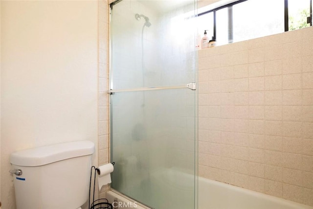 bathroom with toilet and combined bath / shower with glass door