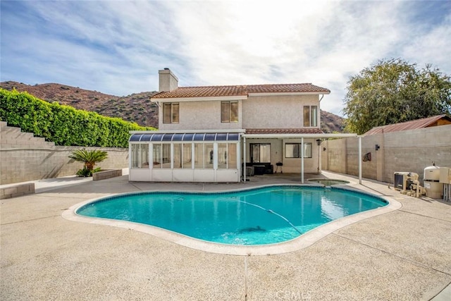 view of pool with a sunroom, a mountain view, and a patio area