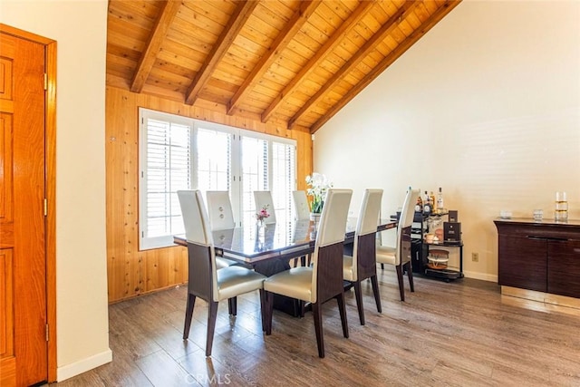 dining space featuring vaulted ceiling with beams, wood walls, hardwood / wood-style floors, and wooden ceiling