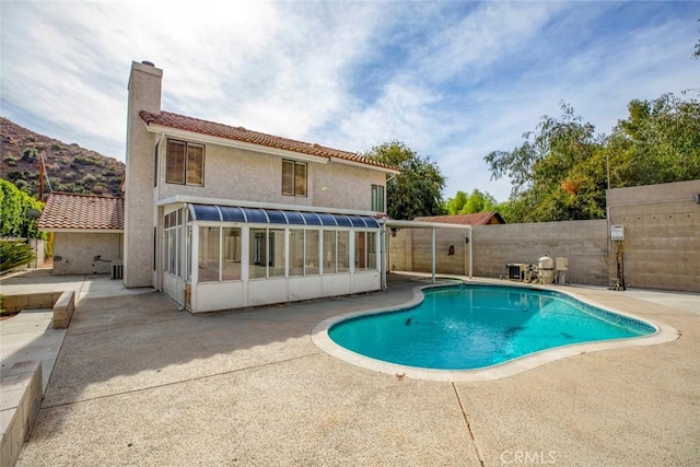 view of pool with a sunroom and a patio