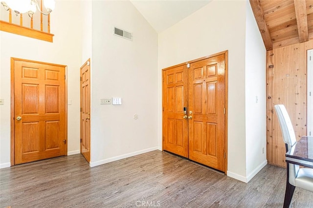 entrance foyer with wood ceiling, beam ceiling, high vaulted ceiling, a chandelier, and hardwood / wood-style floors