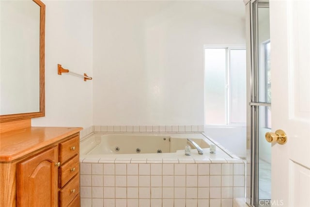 bathroom featuring tiled tub and vanity